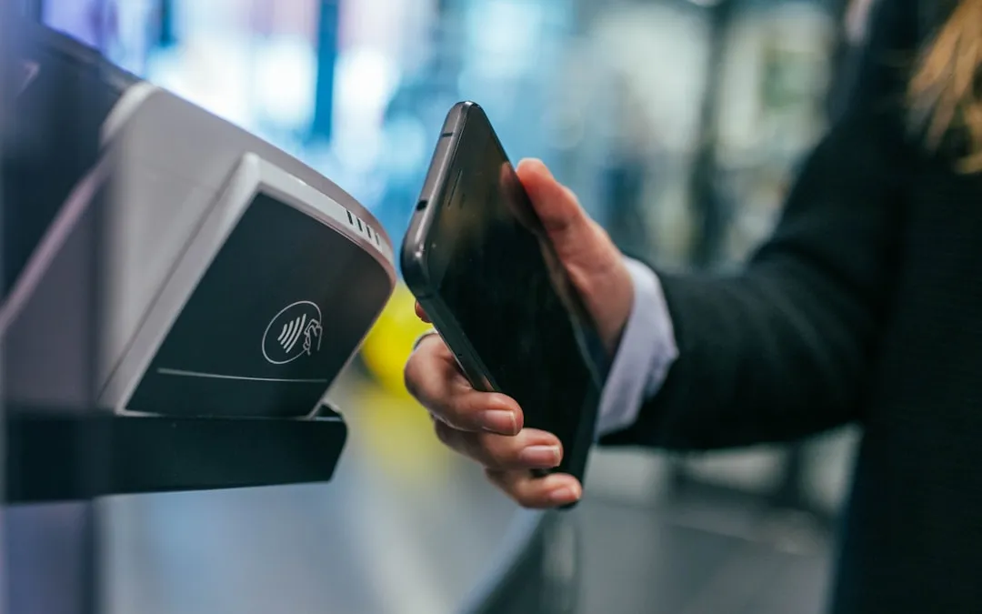 شخص يستخدم هاتفه الذكي لإتمام عملية دفع عبر تقنية NFC بدون تلامس