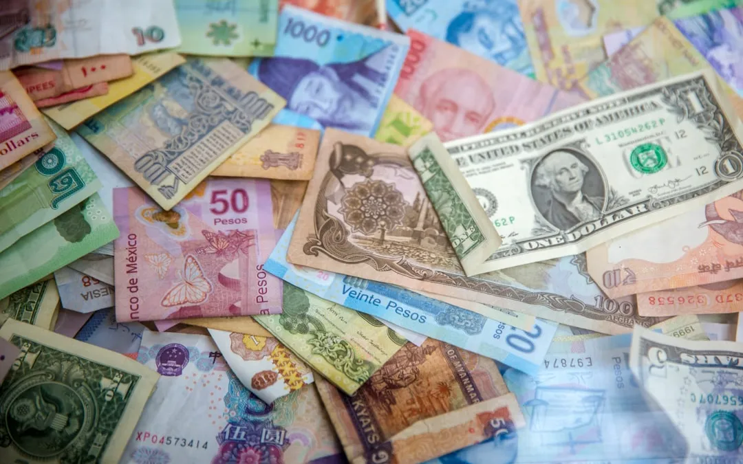 مجموعة متنوعة من الأوراق النقدية الدولية موزعة على سطح مستوٍ، ترمز للتحويلات المالية العالمية