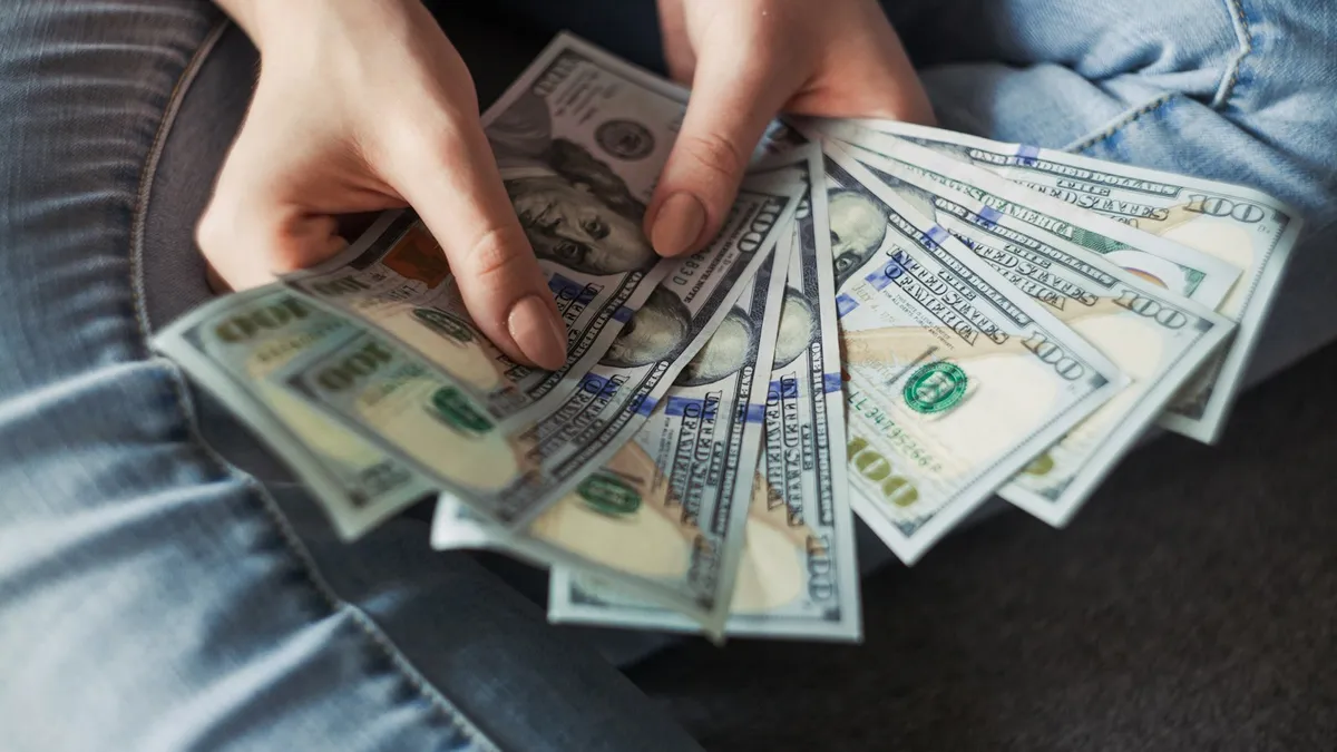 مجموعة من الأوراق النقدية الدولارية ممسوكة باليد